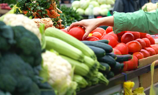 Hands of a female picking fresh vegetables from a cart